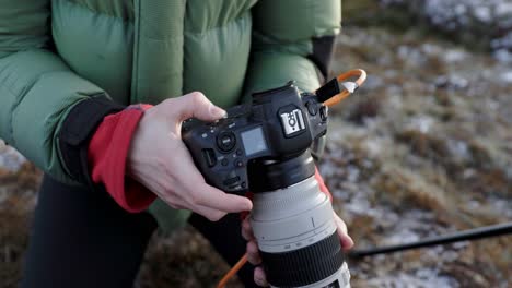 Guy-setting-up-Canon-camera-with-tele-zoom-lens-using-tether-photography,-outdoor-photographer