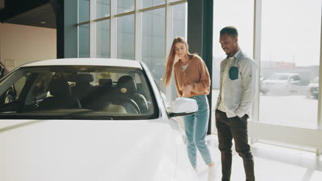 una pareja mirando un coche nuevo en una sala de exposiciones