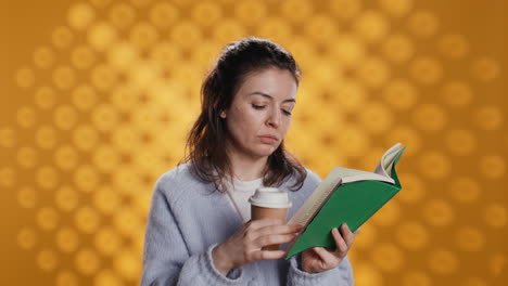 woman reading book, turning page and holding coffee, studio background