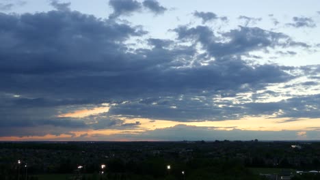 amazing time-lapse of clouds above dark suburb at sunset