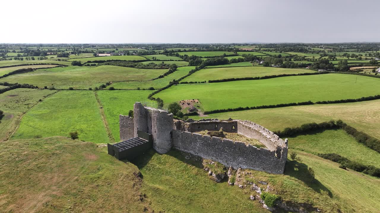 Incredibile ripresa aerea con drone delle rovine del Castello di Roche su una collina e paesaggio rurale irlandese