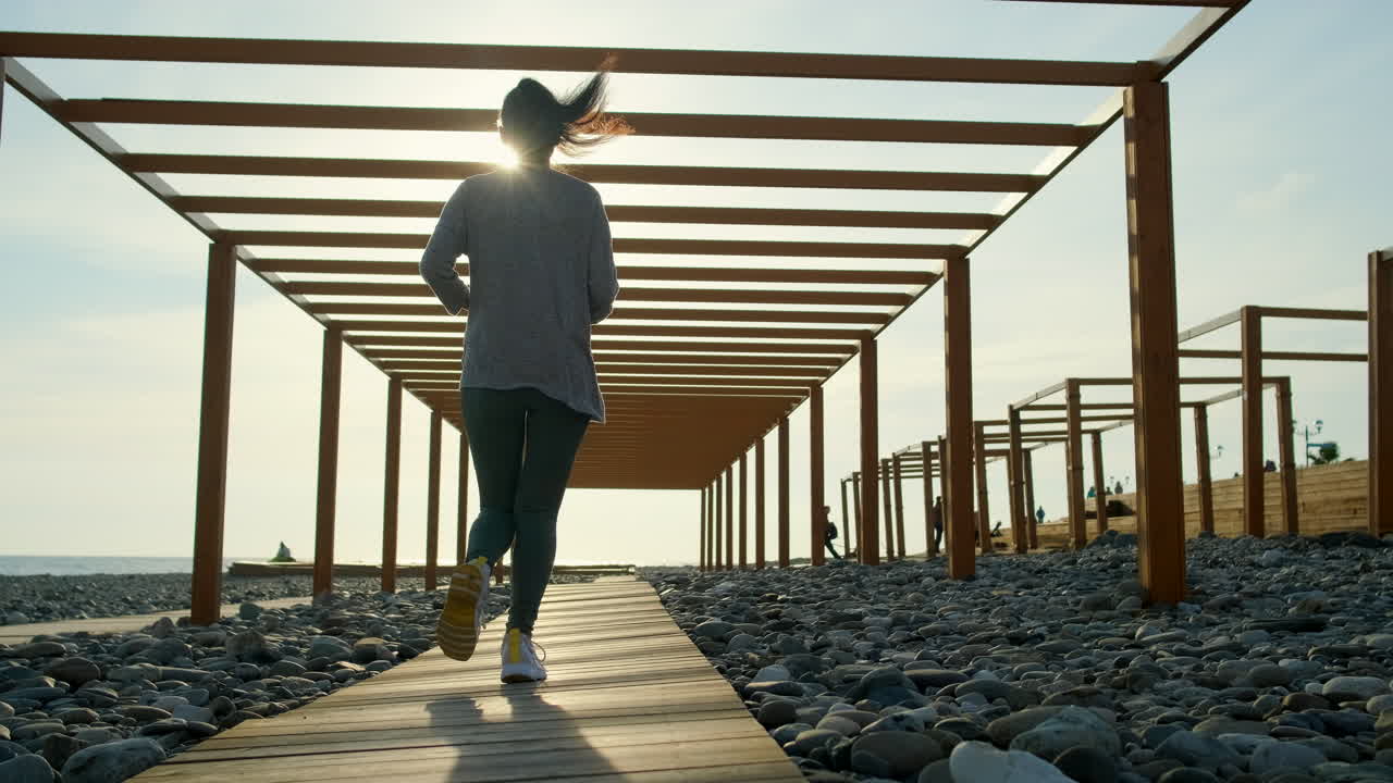 Woman Running on a Wooden Path at the Beach