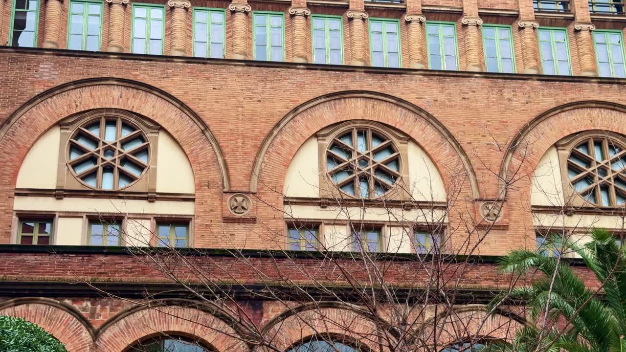 Facade of the Església de l’Hospital de la Santa Creu i Sant Pau revealed by a horizontal pan in Barcelona, Catalonia, Spain, showing Romanesque–Byzantine revival brick architecture and arched windows