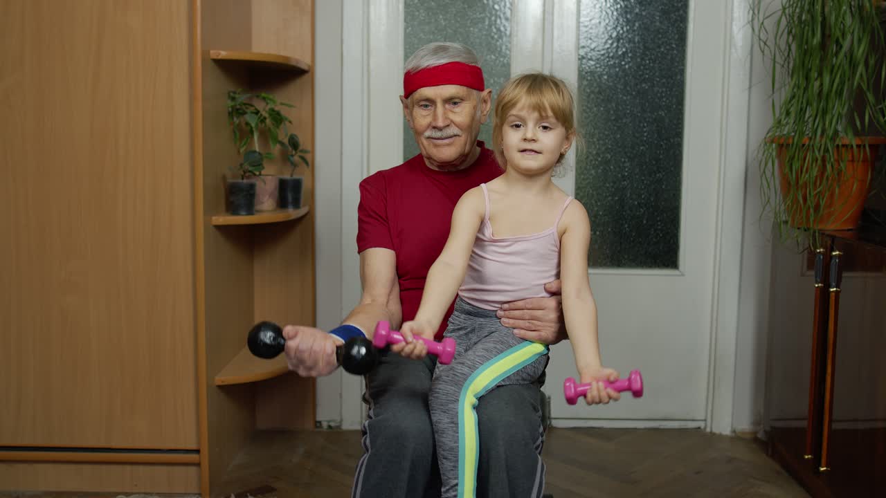 Aktiver Großvater und Senior mit kleinem Mädchen beim Fitness-Hanteltraining