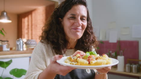 a woman holding a plate of pasta