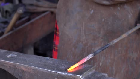 A-blacksmith-using-his-hammer-on-an-anvil-in-his-forge,-workshop,-close-up