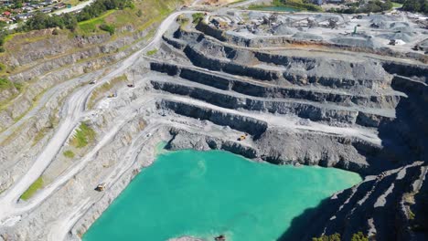 aerial footage of a terraced quarry with vibrant turquoise water, surrounded by lush greenery under bright daylight