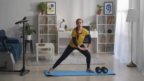 aerobics and gymnastics training at home teen girl is crouching on legs on sides fitness in living room doing exercises for health of body