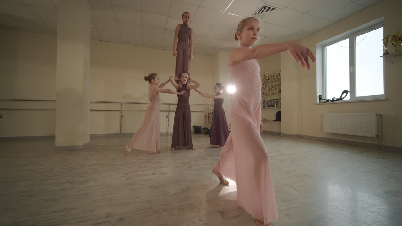 un grupo de jóvenes estudiantes de ballet con ropa de baile negra practicando posiciones en un amplio estudio de ballet con pisos de madera y barras montadas en la pared. expresiones enfocadas y movimientos sincronizados.