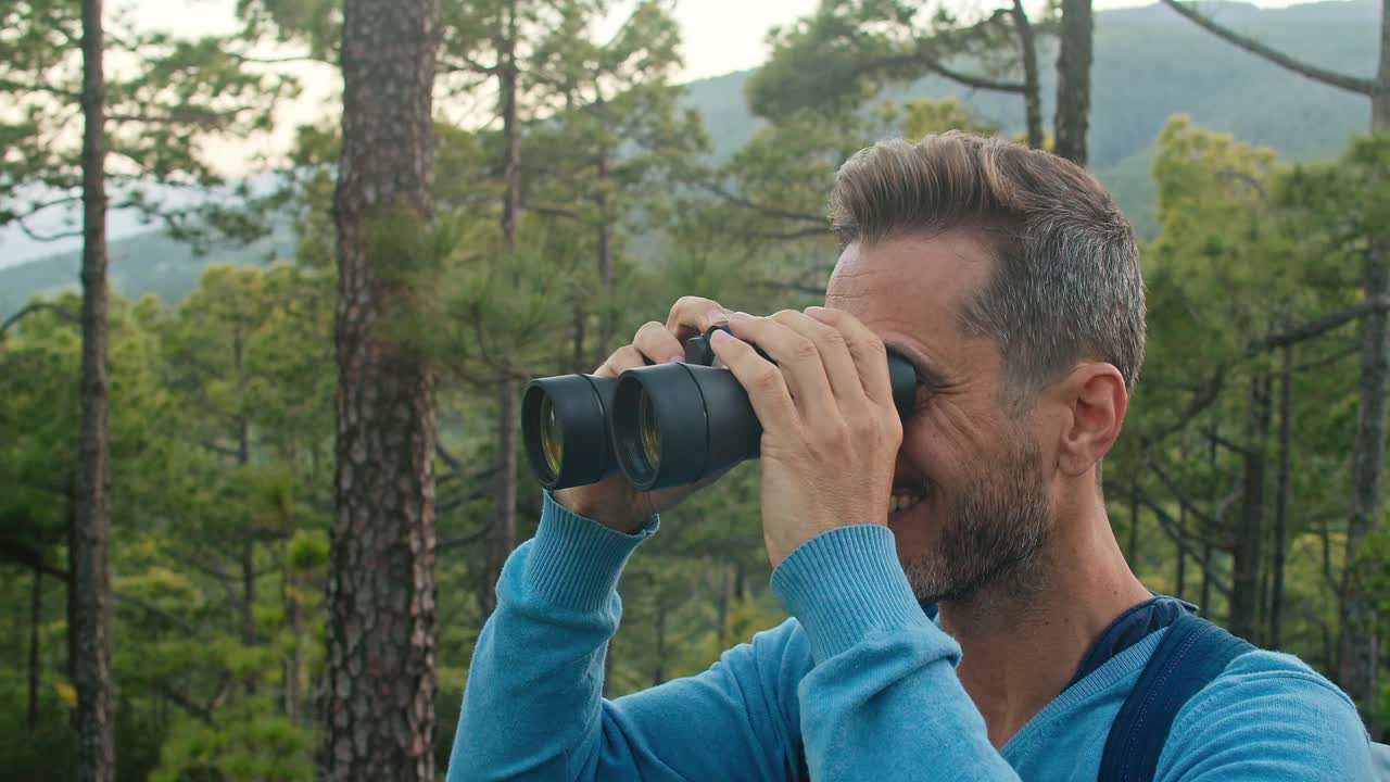 hombre feliz admirando la naturaleza a través de binoculares