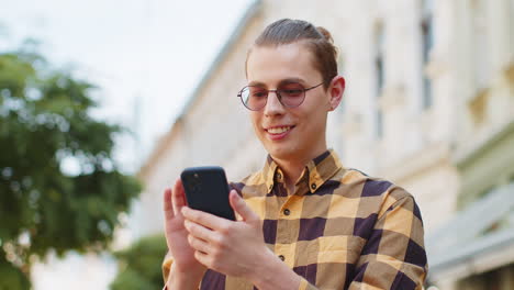 happy young man tourist using smartphone internet social media web app chatting on urban city street