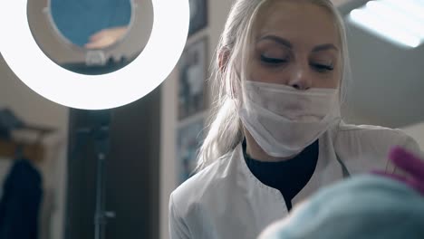 cosmetologist checks client eyebrows at led lamp light