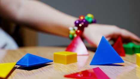 child's hand playing with colorful geometric shapes