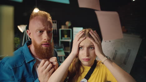 upset young team arguing near idea board in office. couple despairing near board