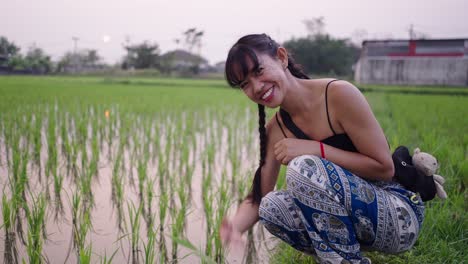 smiling woman crouching in a green rice field