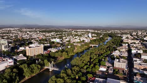 Vista-Aérea-Del-Río-Tamazula-Y-El-Paisaje-Urbano-De-La-Ciudad-De-Culiacán,-Hora-Dorada-En-Sinaloa,-México