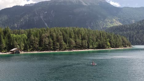 Menschen-Stand-Up-Paddle-Board-Auf-Einem-See-Blindsee-In-Den-Bergen-In-Österreich-Tirol,-Hütte-Am-See-Im-Hintergrund