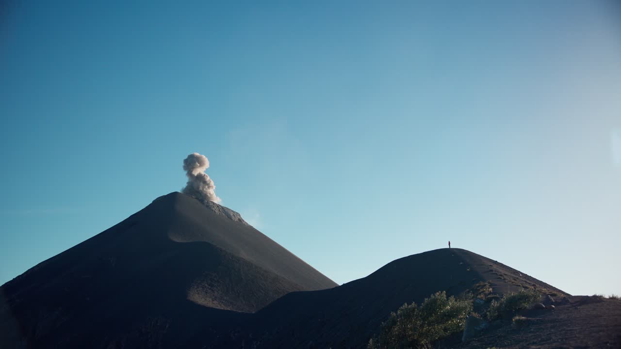 persona soltera de pie en la cresta de un volcán de fuego en erupción