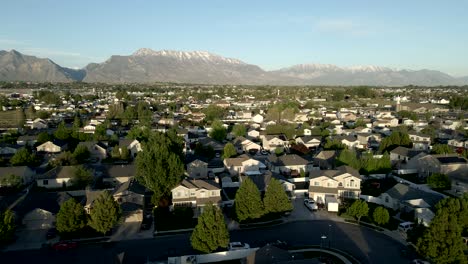 casas unifamiliares en una comunidad suburbana en un valle debajo de las montañas rocosas - vista aérea de retroceso