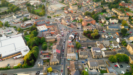 a drone records heckmondwike, uk, with industrial buildings, bustling streets, and the old town center on a summer evening