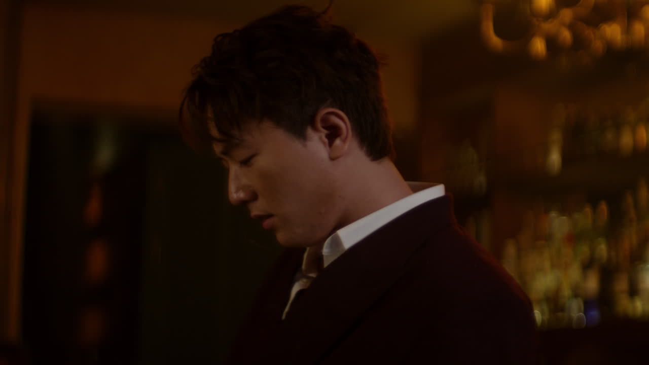 Contemplative man in a bar, dressed in a dark suit, gazing down thoughtfully