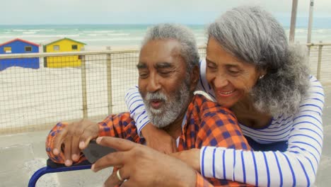 front view of active senior african american couple taking selfie with mobile phone on promenade 4k