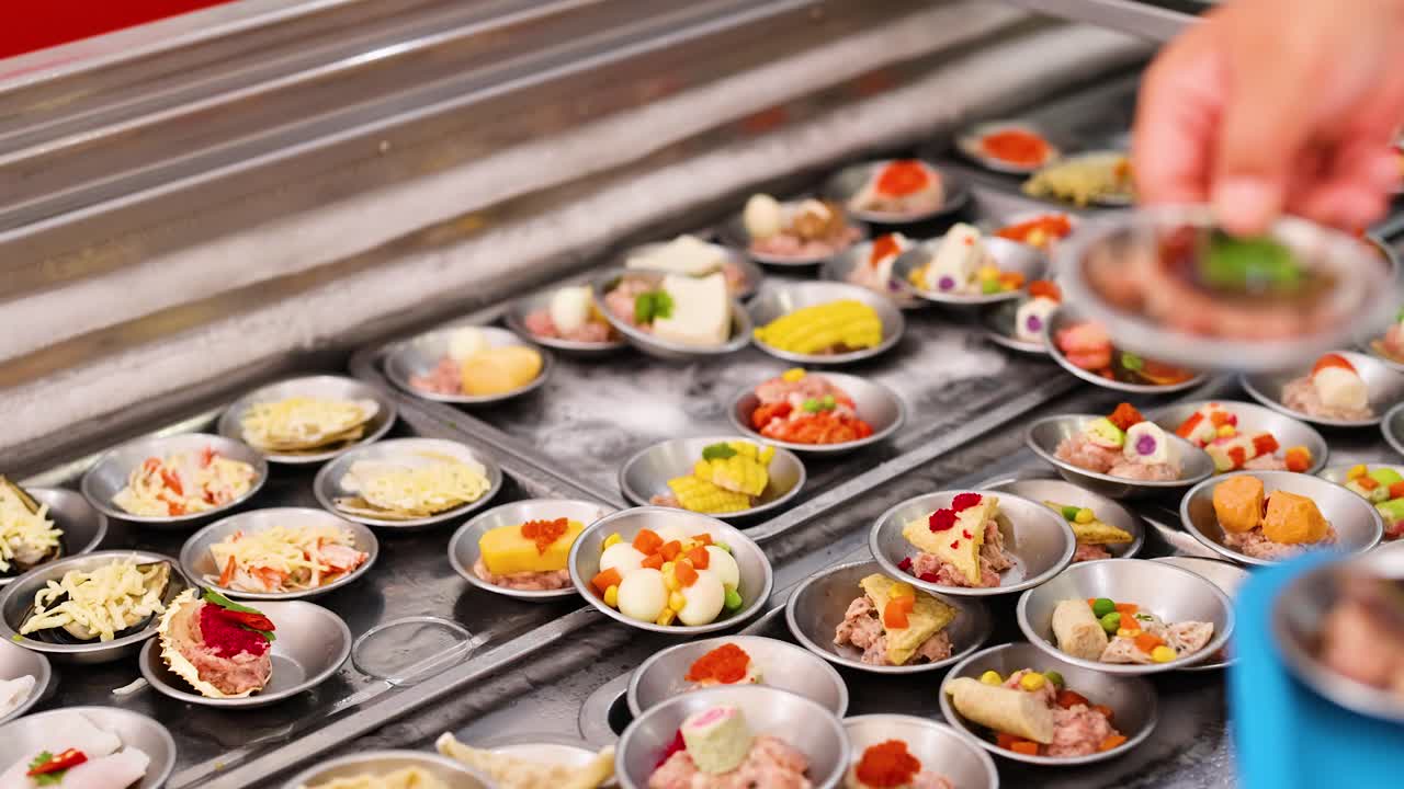 A chef arranges colorful dim sum in a bustling Phuket market. Bright lighting highlights the vibrant ingredients and meticulous preparation