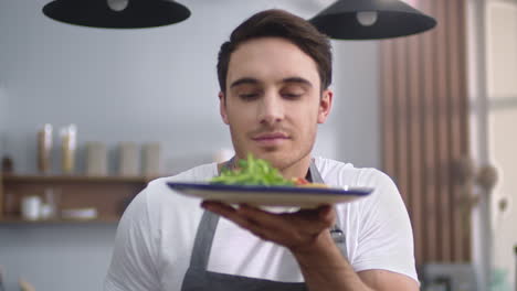 hombre cocinando ensalada con olor en la cocina de casa. chef alegre presentando comida saludable