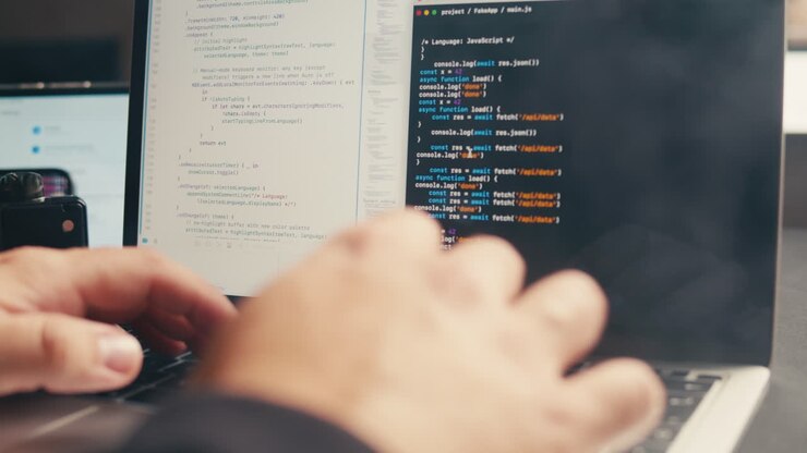 Nærbillede af hænder der skriver kode på en bærbar computers tastatur