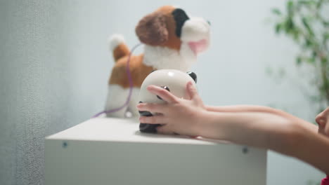 child takes full piggy bank in form of panda from rack