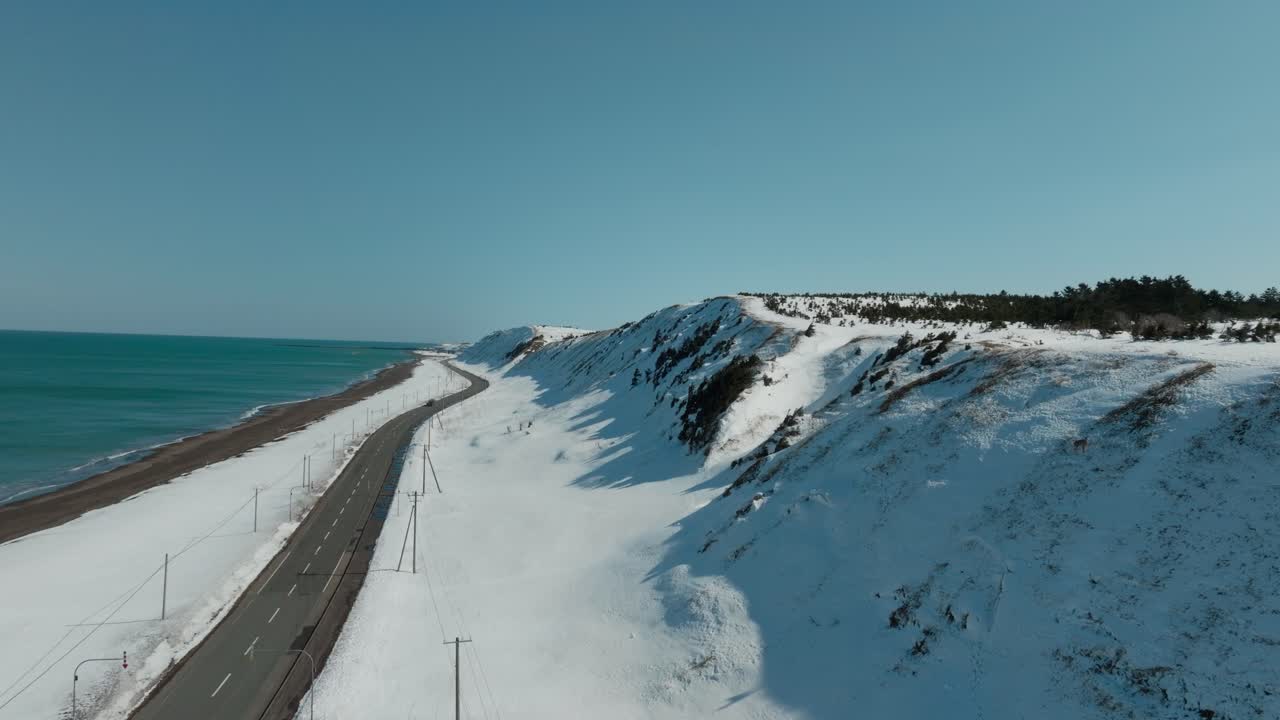 Car Driving Through The National Route 238 Along The Sea And Snowy Hill In Wakkanai, Japan. -aerial shot