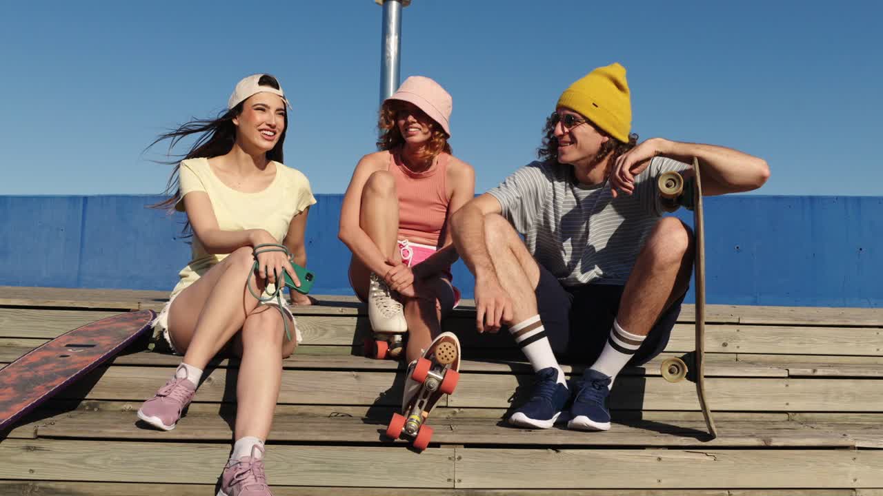 Amici con skateboard e pattini a rotelle seduti insieme