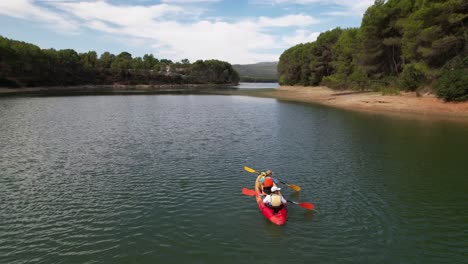 father and daughter having a blast in a red and yellow kayak in a green water river