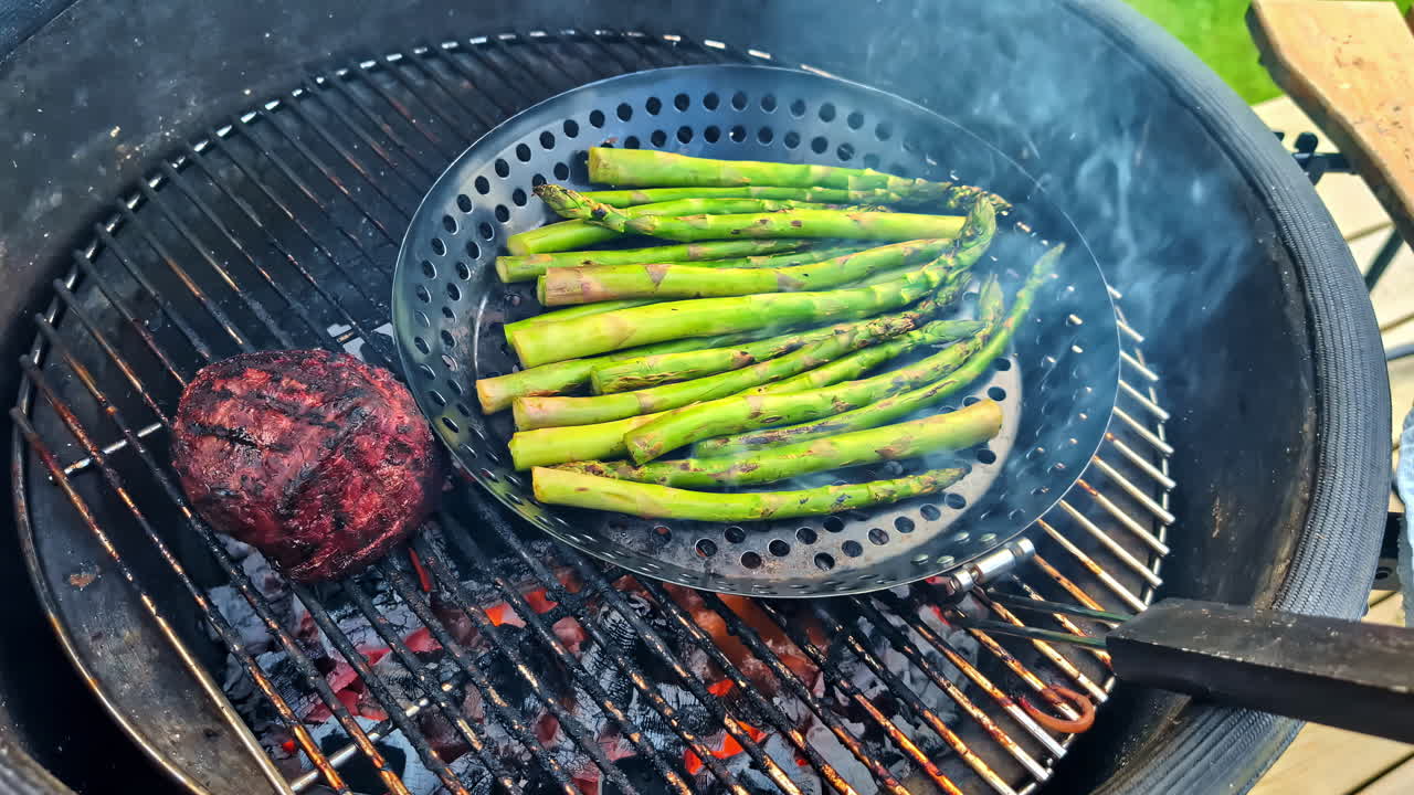 Vegetables on grill with visible char lines and green asparagus cooking over flame