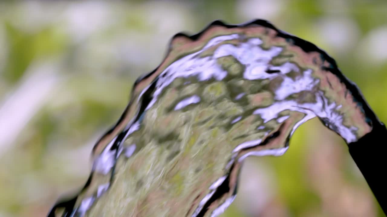 el agua fluye fuera de la parte superior de la manguera de goma empapando los alrededores