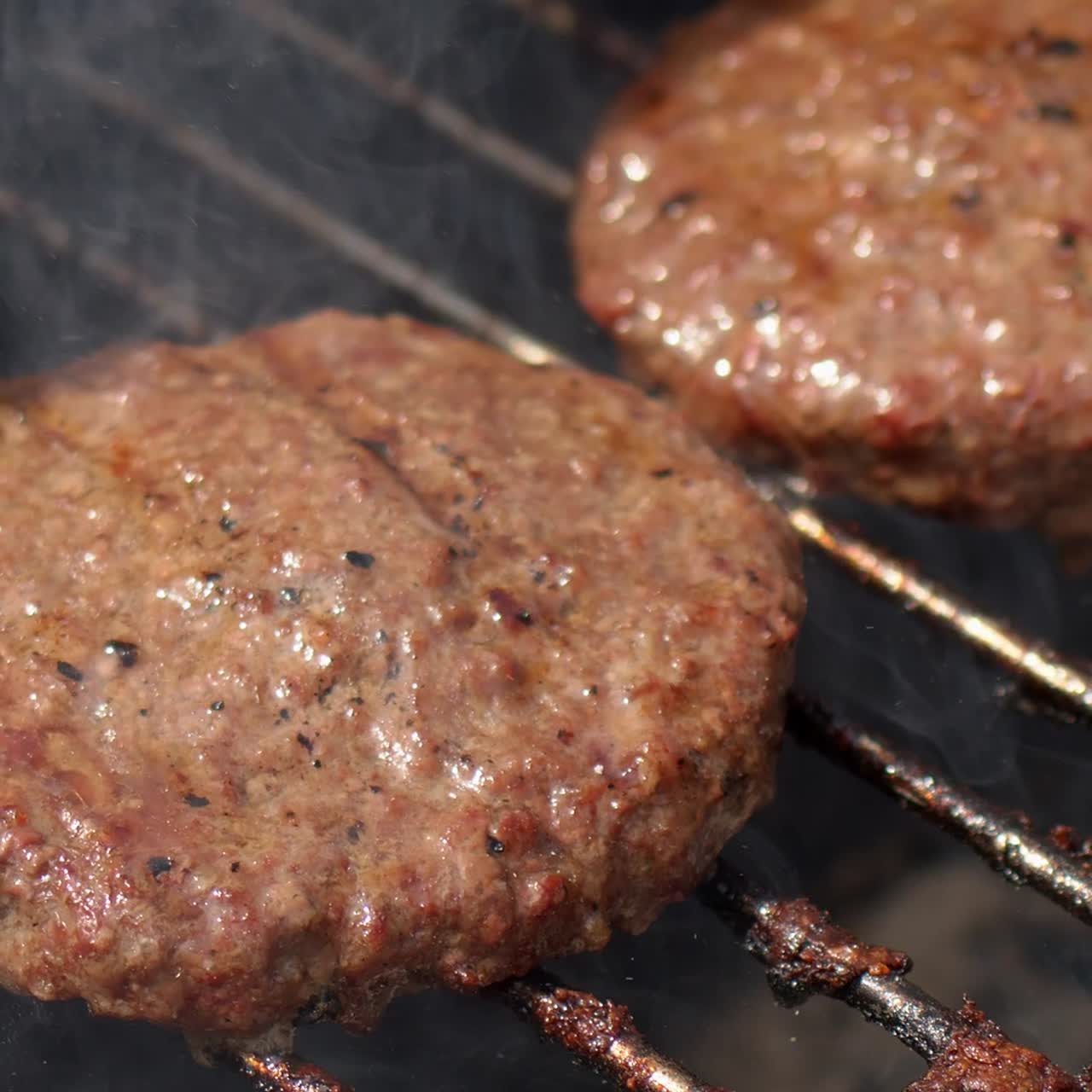 Tasty two hamburger meat frying on smoking hot barbecue  Slow motion video