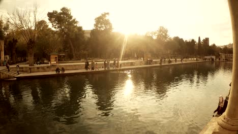 sun shines on pool of sacred fish in mosque of halil-ur-rahman some girls feed fish urfa