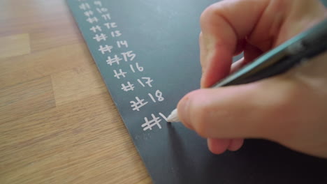 hand writing numbers on chalkboard using white pen