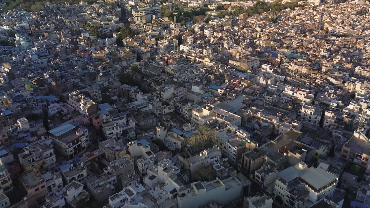 Vista aerea di case fittamente raggruppate a Udaipur, Rajasthan, che rivela un vasto tessuto urbano di tetti, strade strette e una calda luce serale che si estende sulla città