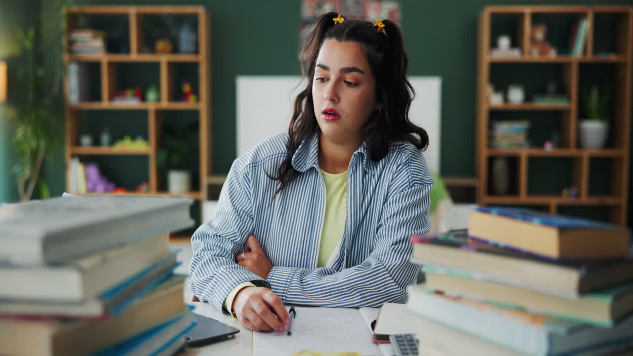 A tired woman studying at a desk with books