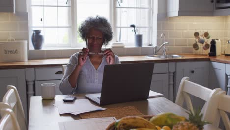una mujer afroamericana mayor estresada usando una computadora portátil y calculando las finanzas en casa