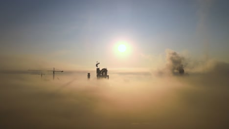 aerial view of cement factory with high concrete plant structure and tower crane at industrial manufacturing site on foggy evening. production and global industry concept