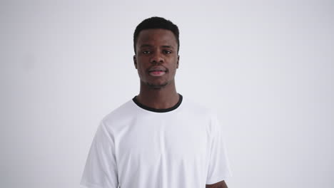 un retrato de un feliz jugador de fútbol de un grupo étnico africano en un uniforme blanco sobre un fondo blanco está mirando a la cámara. la cámara se mueve hacia atrás desde el headshot al plan principal