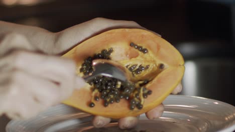 woman scooping seeds from a papaya