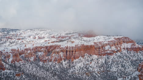 time lapse, bryce canyon national park on winter season, snow capped red rock cliffs and hoodoos under clouds, utah usa