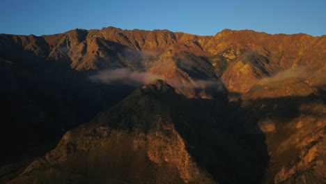 cirrus clouds between the orange colored mountains during sunset