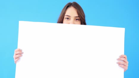 Beautiful-woman-holding-blank-placard-on-blue-background