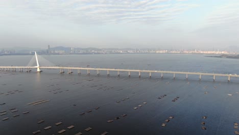 Hong-Kong-Shenzhen-Bay-Bridge-with-Tin-Shui-Wai-buildings-in-the-horizon-and-Fish-and-Oyster-cultivation-pools,-Aerial-view