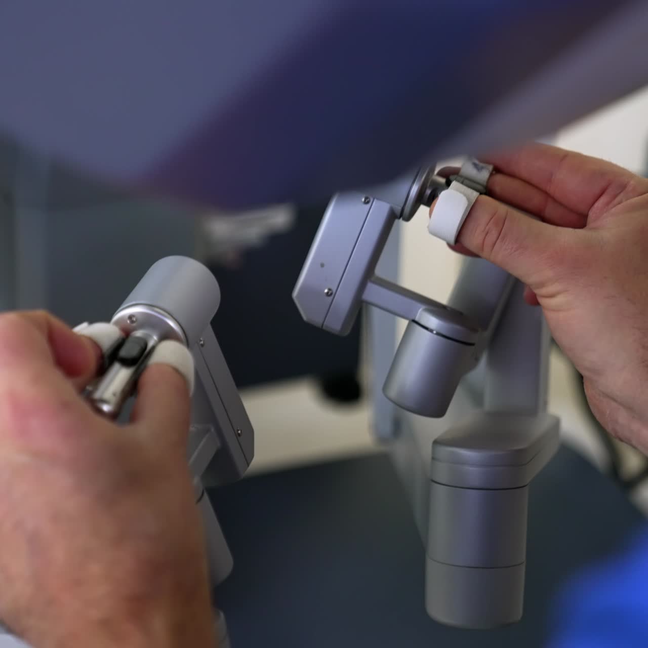 Surgeon moving master manipulators sitting at control unit. Doctor carrying out the operation of minimal invasion using advanced technology equipment. Close up