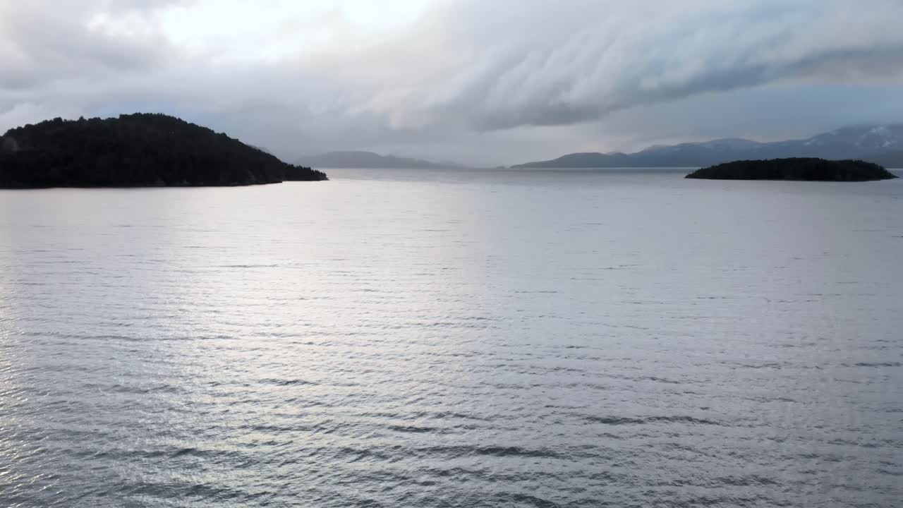 눈으로 인 산꼭대기와 구름의 배경으로 둘러싸인 파타고니아 호수의 상공 전망